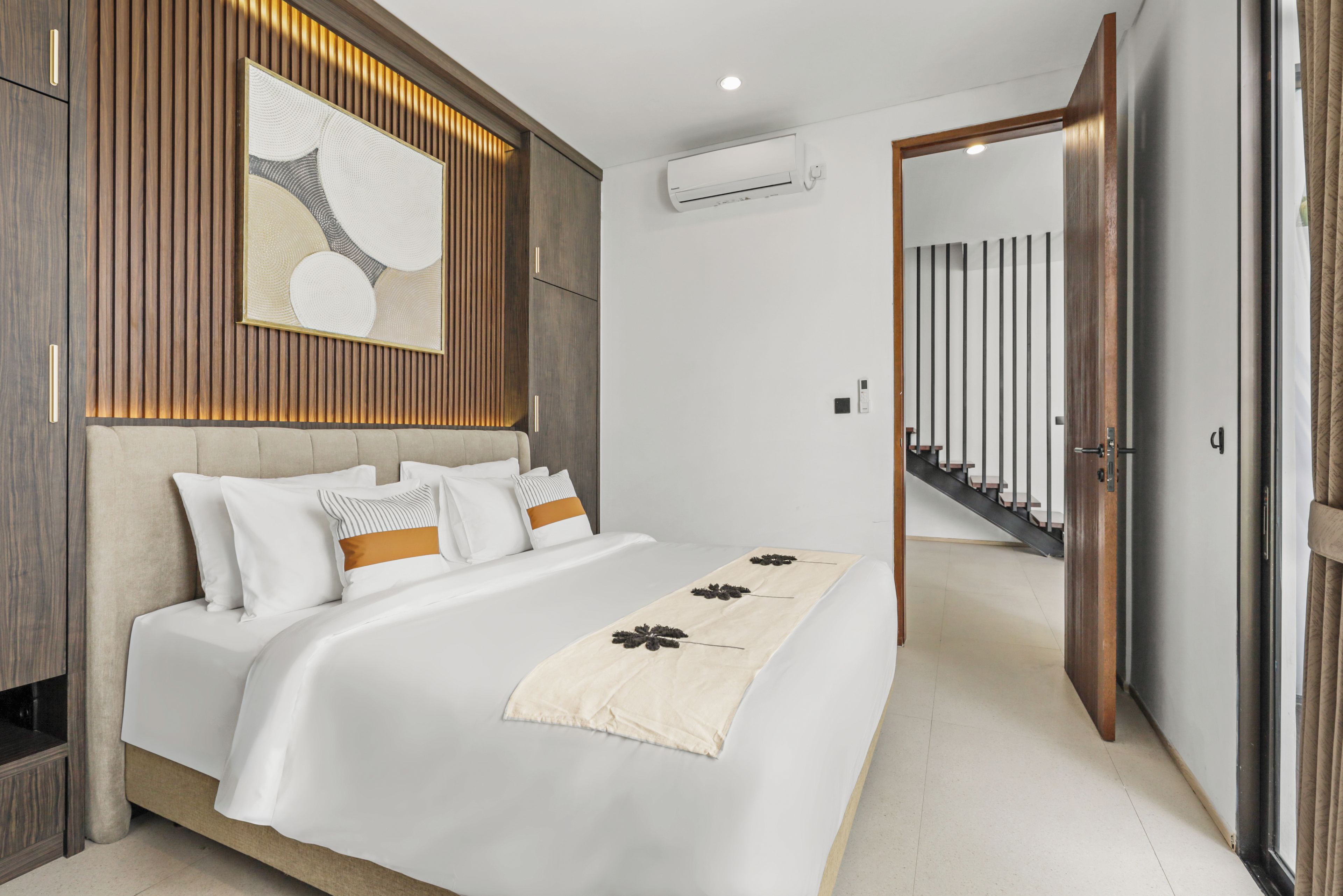 Un dormitorio moderno con una cama grande, paneles de madera y vista a una escalera.