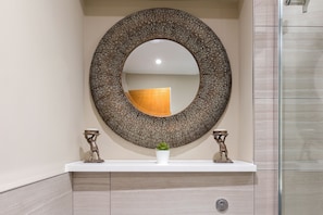 A bathroom with a round mirror, two small decorative items, and a potted plant on the vanity. - Delightful 2 Bed Flat in Shoreditch (London)