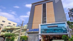 A hotel with a modern design, featuring a prominent vertical wooden panel and a glass facade. - Myspace Dhruva Inn (Bengaluru)
