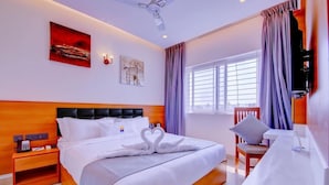 A hotel room with a bed, bedside table, a desk, and a chair. - Myspace Dhruva Inn (Bengaluru)