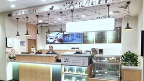 En kaféinredning med en receptionsdisk, en digital meny och ett utställningsbord för kaffeprodukter.
