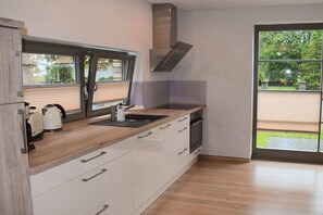 Eine moderne Küche mit großem Fenster, Einbauofen und Dunstabzugshaube aus Edelstahl.