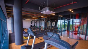 A modern gym with treadmills, weight machines, and a large window offering a view of the outdoors. - Timurbay Seafront Apartment by My Seasons (Kuantan)
