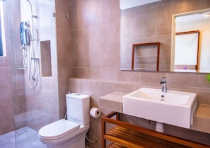 A bathroom with a shower, toilet, sink, and a wooden bench. - Timurbay Seafront Apartment by My Seasons (Kuantan)