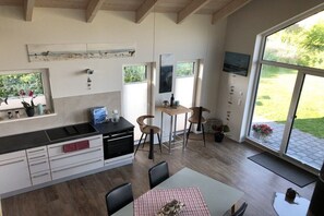 Une cuisine moderne avec un coin repas, de grandes fenêtres et une vue sur l’extérieur.
