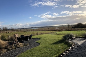 A landscaped outdoor area with a gravel path, seating, and an easel, overlooking a rural landscape. - Painters' Corner Hohwacht (Hohwacht)