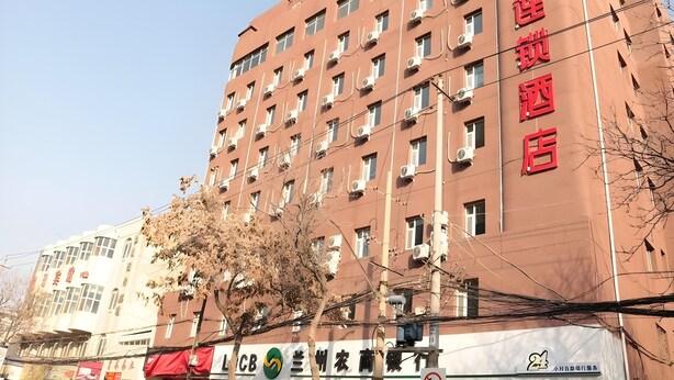 Un immeuble à plusieurs étages, doté d’une façade rouge et de nombreuses unités de climatisation à l’extérieur.