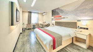 A hotel room with a large bed, a desk, a chair, a small table, and a painting of a mountain landscape. - Thank Inn Hotel Gansu Lanzhou Xigu District Heshui Road (Lanzhou)