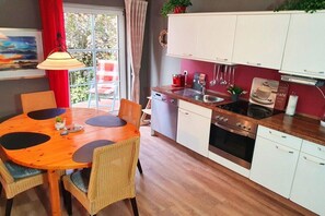A compact kitchen with a dining area, a sink, and a stove. - Electricity View No. 7 (Seeheilbad Zingst)