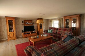 A living room with a sofa set, a television, wooden cabinets, and a red rug. - Holiday home with 3 bedrooms (Vollerwiek)