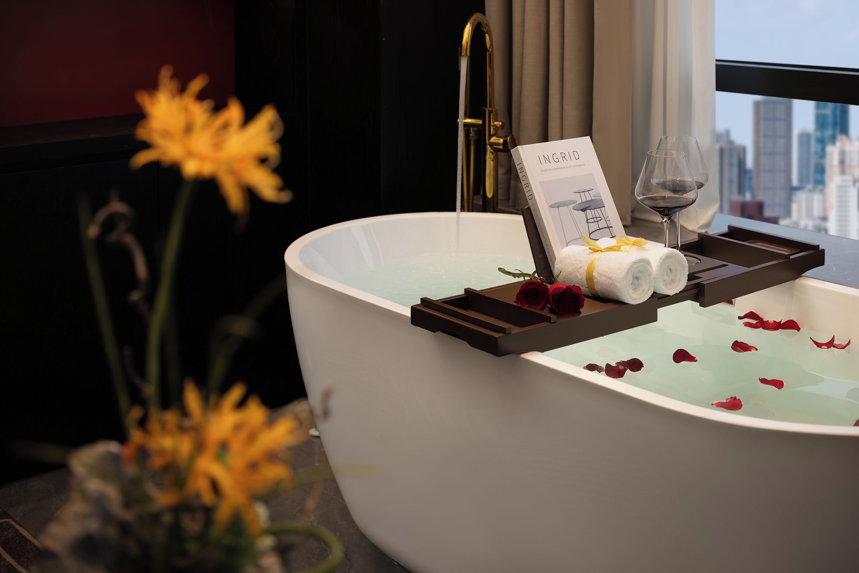 Una bañera con pétalos de rosa, una toalla y una copa de vino.