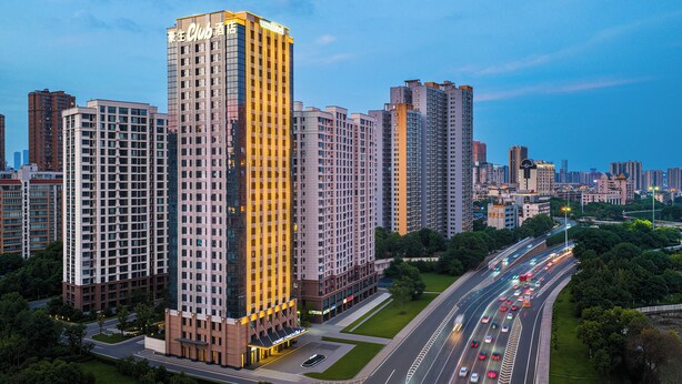 Ein Hochhaus-Hotel mit auffälliger Beschilderung, umgeben von weiteren hohen Gebäuden und einer vielbefahrenen Autobahn.