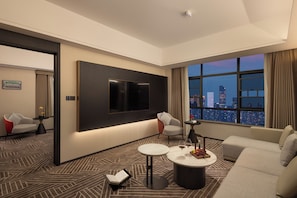 A modern hotel room with a large TV, a sofa, a coffee table, and a city view. - Changsha Howard Johnson Club Hotel (Changsha)