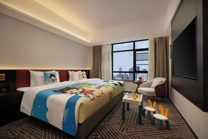 Habitación de hotel con una cama grande, televisión, escritorio con silla y vistas a la ciudad.