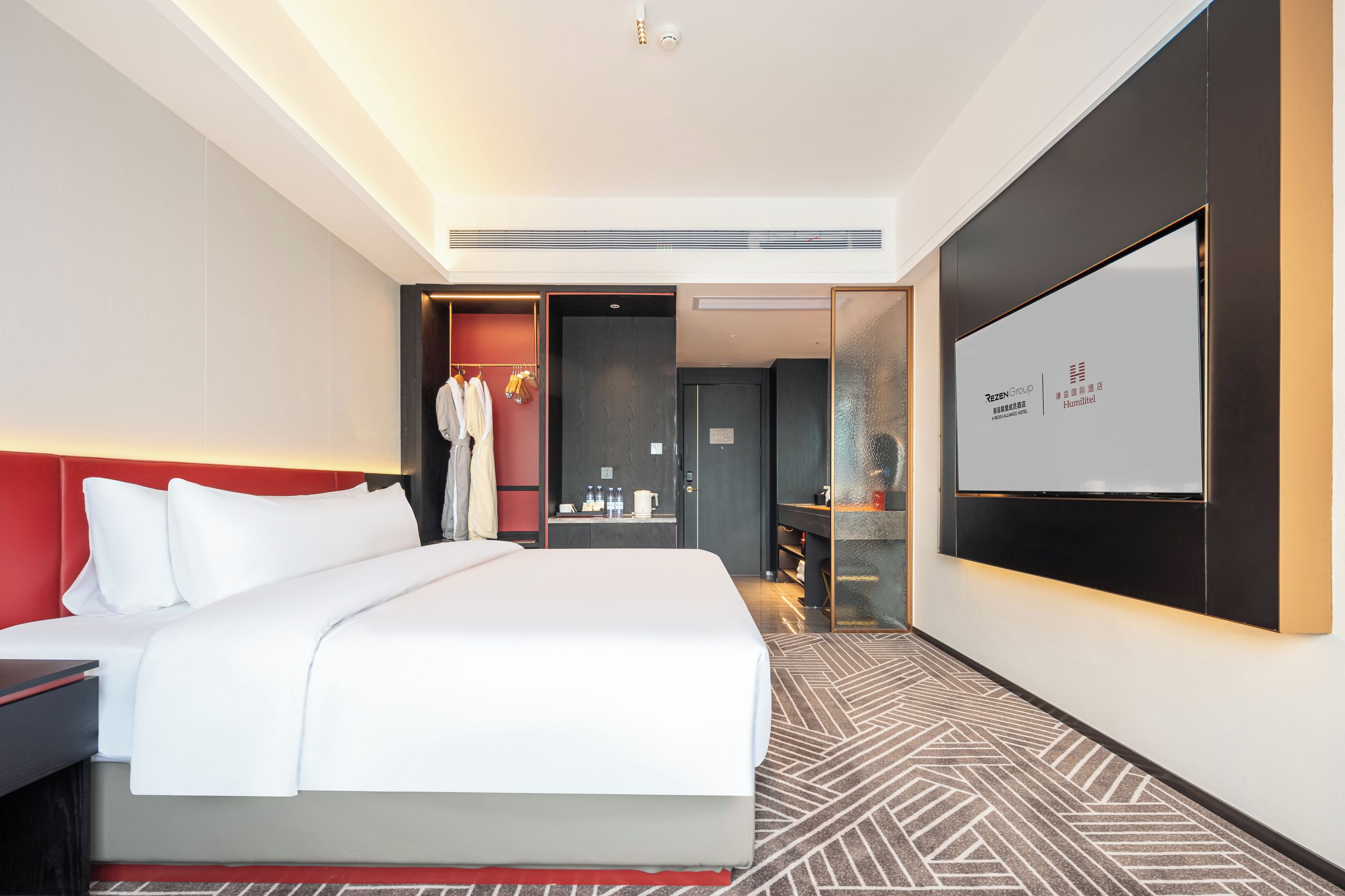 A hotel room with a large bed, a wardrobe, a desk, a mirror, and a television.