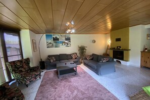 Ein Wohnzimmer mit einer Sofagarnitur, einem Couchtisch, einem Kamin und einer Wand mit Bildern.