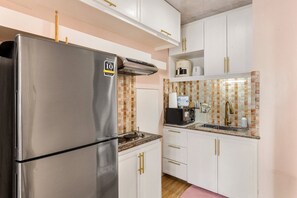 A compact kitchen with white cabinets, a stainless steel refrigerator, a microwave, and a coffee maker. - Spacious 2BR BGC Stay City View Fort Victoria Family & Group Friendly Stay (Taguig)