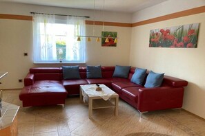 A living room with a red sectional sofa, a small table, and a window with curtains. - Holiday apartment with 4 bedrooms (Lübbenau)