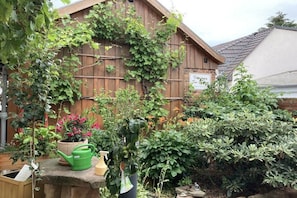 A garden with a wooden fence, potted plants, and a stone ledge with gardening tools. - Holiday apartment with 4 bedrooms (Lübbenau)