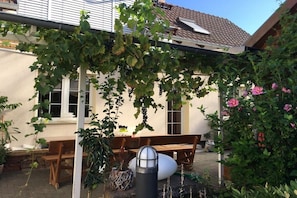 A covered outdoor seating area with a pergola, wooden benches, and potted plants. - Holiday apartment with 4 bedrooms (Lübbenau)