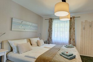 Une chambre d’hôtel avec un lit, une table de chevet, une lampe, un tableau au mur et une fenêtre avec des rideaux.