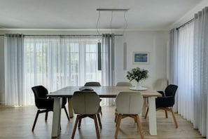 Un coin repas avec une table en bois, six chaises et un vase rempli de fleurs.