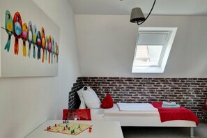 A room with a loft bed, a chessboard on a table, a colorful bird painting, and a skylight. - House Sorgenfrei Holiday Home No. 7 (Travemünde)