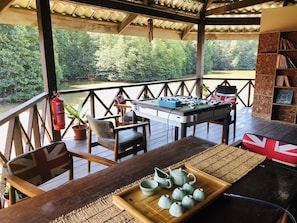 Uma área de deck com mesa de futebol, assentos e vista para um rio.