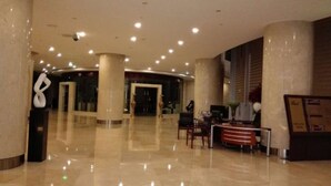 Een hotel lobby met een receptiebalie, een zithoek en een grote zuil.