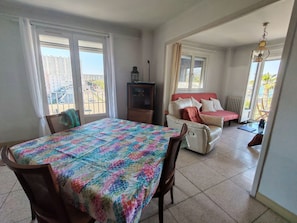 Ein Zimmer mit Esstisch, einer Couch und einem Fernseher.