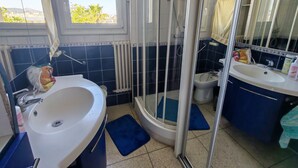 Un baño con ducha, lavamanos y espejo.