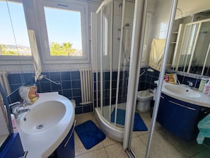Ein Badezimmer mit Dusche, Waschbecken und Spiegel.