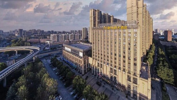 A high-rise building with multiple floors, surrounded by trees and a curved road. - Homeinn Superior Hotel (Hefei)