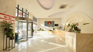 A hotel lobby with a reception desk, a large painting, and a glass door entrance. - Homeinn Superior Hotel (Hefei)