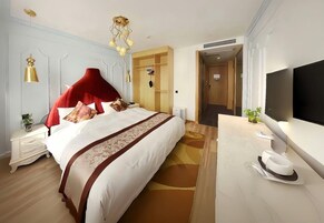 Quarto de hotel com uma cama grande, uma escrivaninha com televisão de tela plana, um guarda-roupa e um espelho.