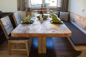 Ein Holztisch mit einer Weinflasche, Gläsern und einer grünen Serviette.