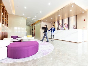 En moderne lobby med en receptionsdisk, siddeområder og en stor lilla skammel.