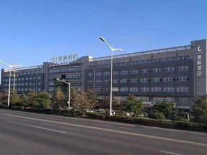 Et hotel med flere etager, moderne facade, mange vinduer og en klar himmel.