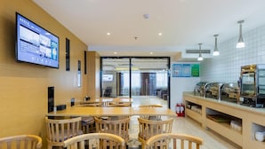 A modern dining area with wooden tables and chairs, a digital menu display, and a kitchen counter with food display. - Lavande Hotels (Weihai)