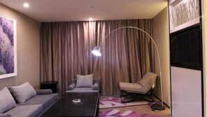 Ein modernes Wohnzimmer mit einer Couch, einem Couchtisch, einer Stehlampe und einem großen Fenster mit Vorhängen.