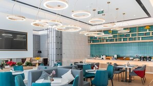 Un intérieur moderne avec un espace salon central, un grand téléviseur à écran plat et une cuisine dotée d’un crédence verte.