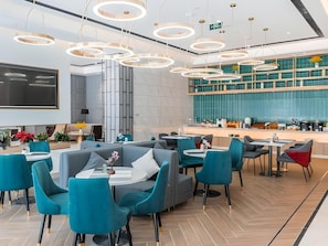 Un interior moderno con una zona de estar central, un televisor de pantalla plana grande y una cocina con salpicadero verde.