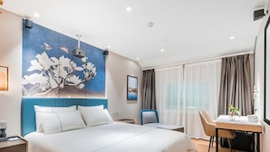 Une chambre d’hôtel moderne avec un grand lit, un bureau et une chaise.