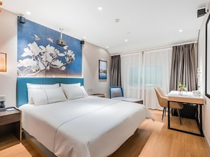Una habitación de hotel moderna con una cama grande, un escritorio y una silla.