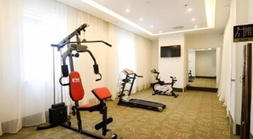 Habitación de hotel con zona de gimnasio que incluye una banca para pesas, una bicicleta estática y una cinta de correr.