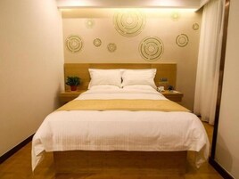 Habitación de hotel con una cama, una mesita de noche, una planta en maceta y una pared con diseños circulares.