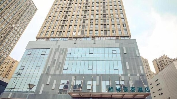 A high-rise building with a modern glass facade and a prominent entrance. - Greentree INN Huaibei Xiangshan District Guogou Square Hotel (Huaibei)