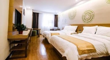 Habitación de hotel con un escritorio de madera, dos camas, una planta en maceta y una pared con diseños circulares.