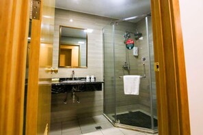 Ein modernes Badezimmer mit Duschkabine aus Glas, einem Waschbecken mit Marmorplatte und einem Spiegel darüber.