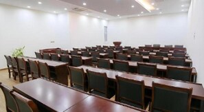 A conference room with rows of tables and chairs, a whiteboard, and a window.